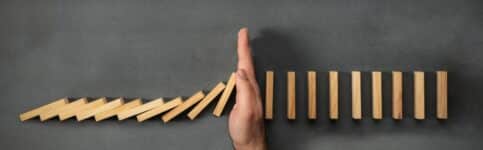 Chain Reaction In Business Concept, Businessman Intervening Dominoes Toppling